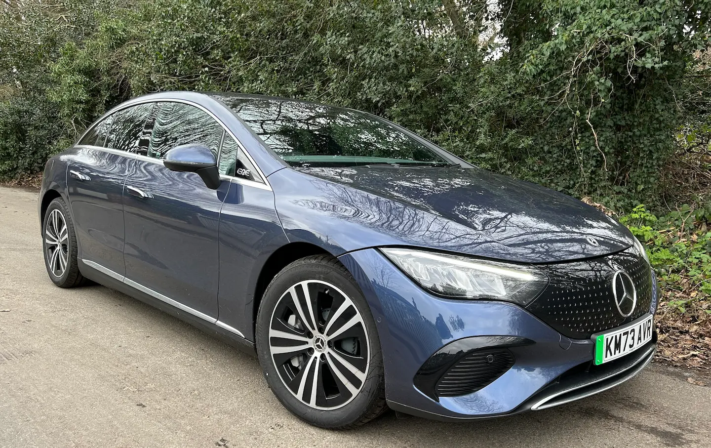 Bílý Mercedes-Benz EQE zaparkovaný před moderní budovou v Praze